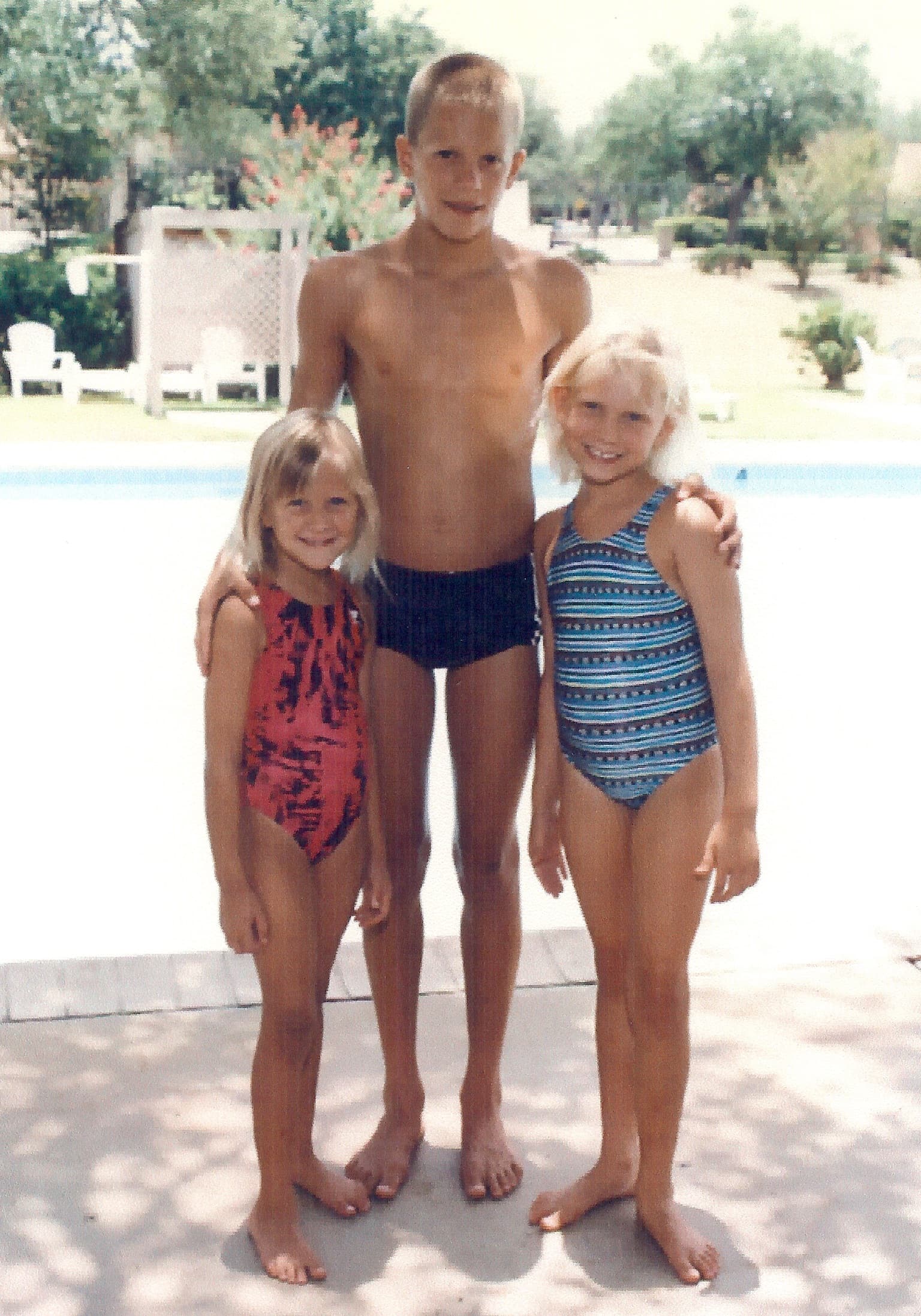 Young Sean standing behind little Meg and Molly in swimsuits at a pool