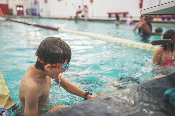 Swimmer catching their breath at the wall between sets during Stroke School practice